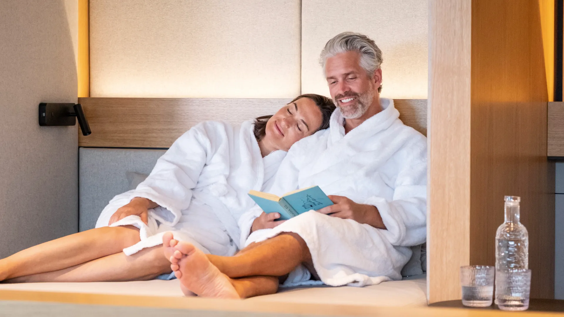 Ein Paar relaxt in Morgenmänteln und mit Buch