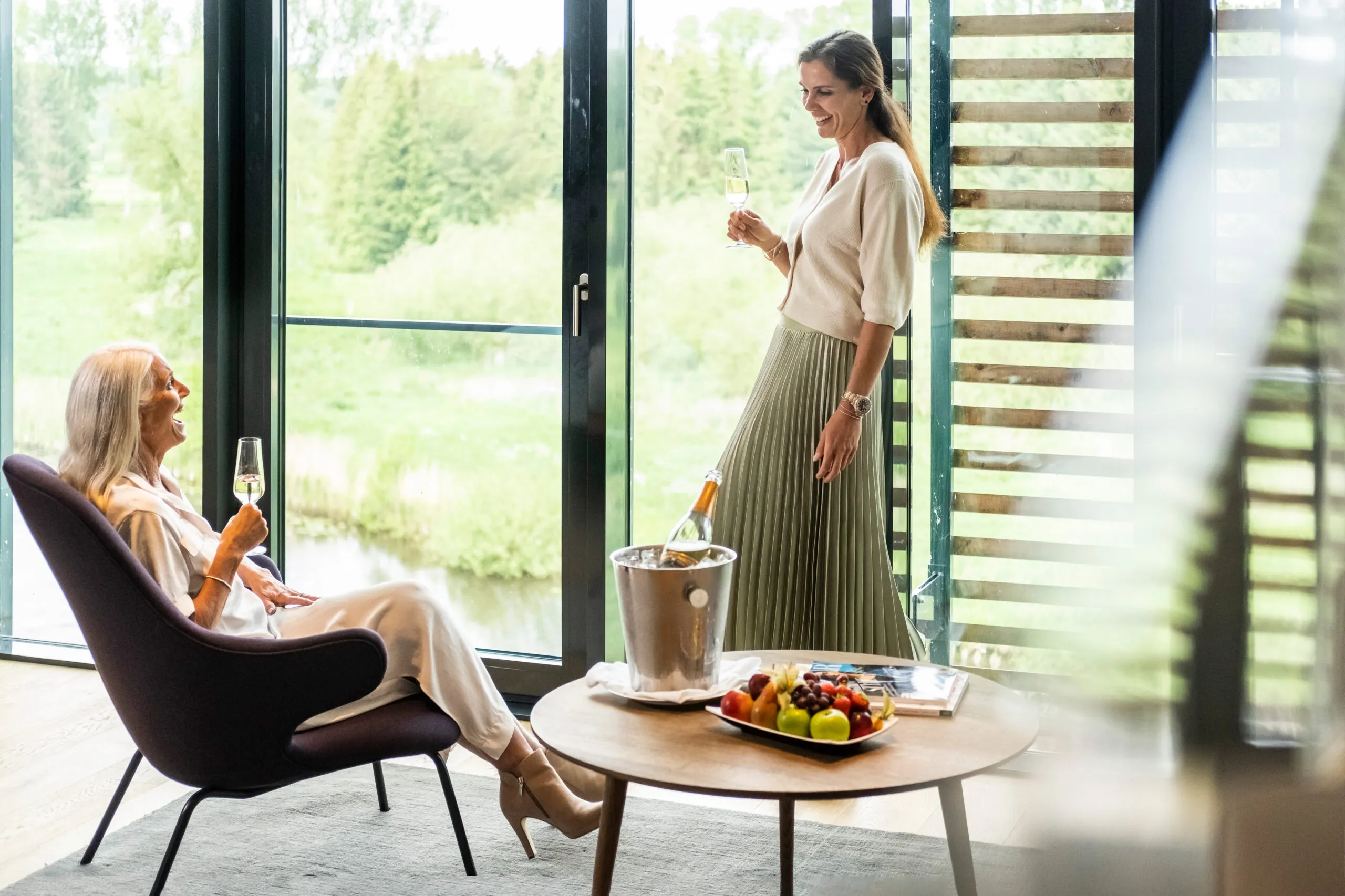 Zwei Frauen mit Sektgläsern vor einer Glasfront